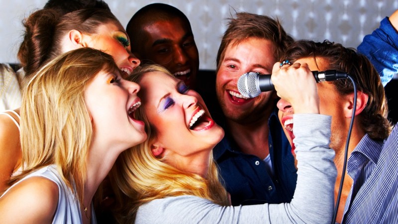 A group of young people singing at a karaoke party.