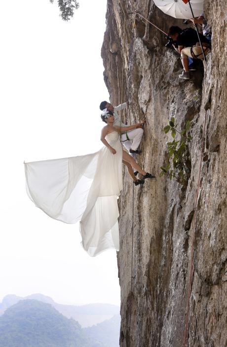 Fang Jing (L) in a wedding gown and her husband, surnamed Zhao, pose for photographs as they hang from a cliff during a rock climbing exercise in Liuzhou, Guangxi Zhuang Autonomous Region October 26, 2013. The couple love outdoor sports and they decided to have their wedding photos taken while rock climbing, local media reported. Picture taken October 26, 2013. REUTERS/Stringer (CHINA - Tags: SOCIETY SPORT) CHINA OUT. NO COMMERCIAL OR EDITORIAL SALES IN CHINA  Picture Supplied by Action Images